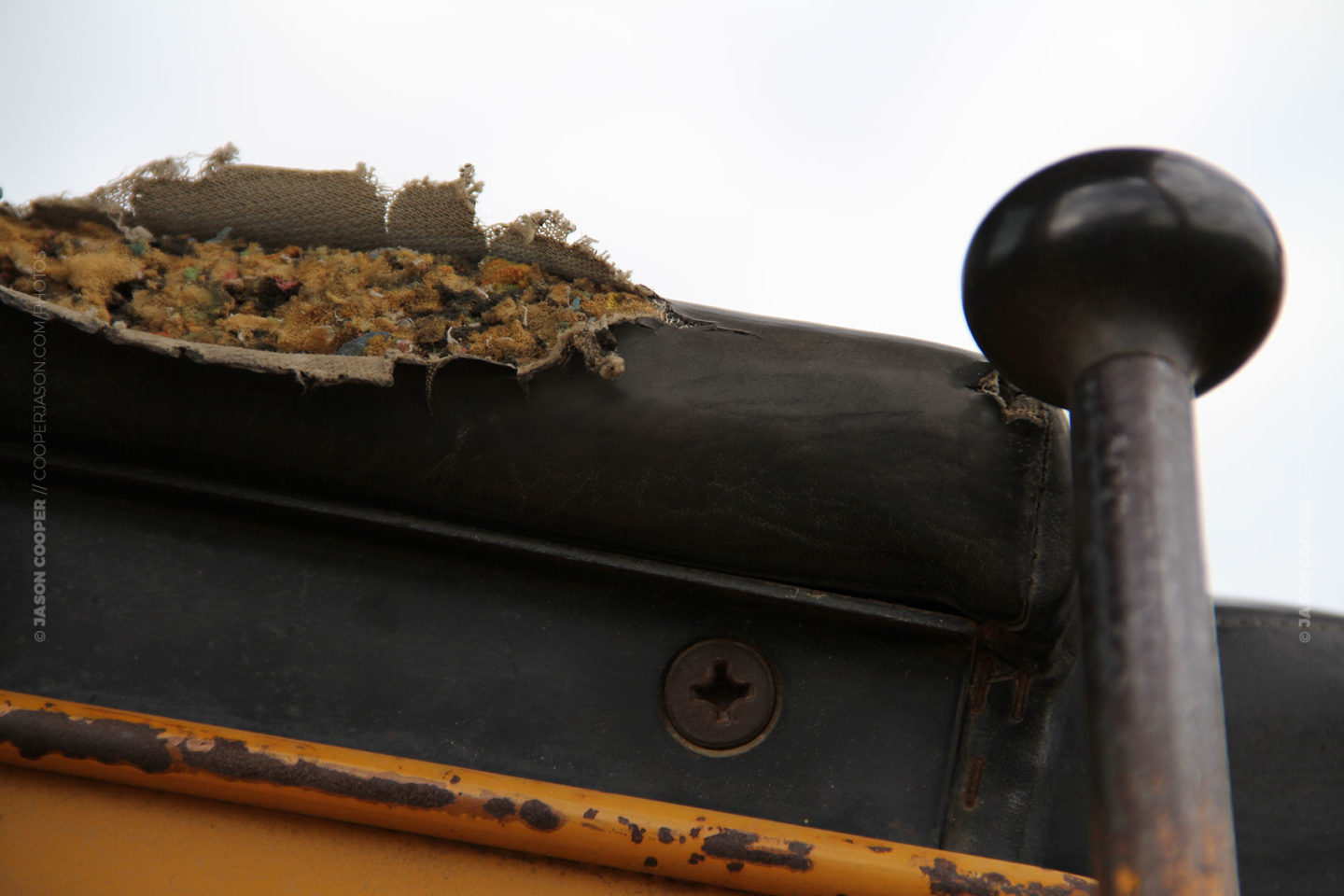 photo of torn armrest on an old yellow bulldozer